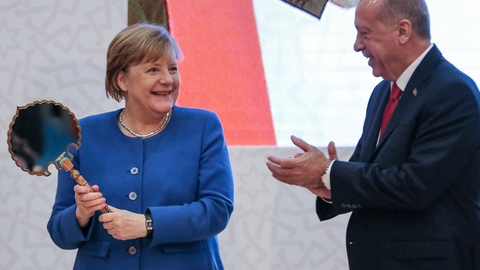 Tysklands forbundskansler, Angela Merkel, viser en gave frem, som hun har fået af den tyrkiske præsident, Recep Tayyip Erdogan, under sit besøg i Istanbul fredag.