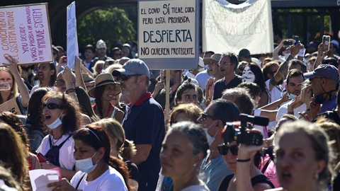 En folkemængde med klappende og jublende mennesker samledes søndag under et enormt gult og rødt spansk falg på Plaza Colon i den centrale del af den spanske hovedstad. De protesterede mod obligatorisk brug af mundbind og andre restriktioner vendt mod covid -19.