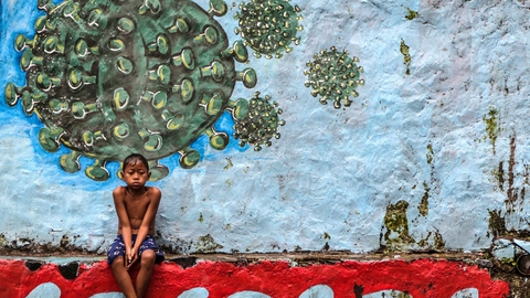En dreng sidder under et murmaleri af coronavirusset i Vestjava i Indonesien. Landet har bekræftet over 278.000 tilfælde af coronasmitte og har ifølge de officielle tal lidt over 10.400 dødsfald blandt smittede.