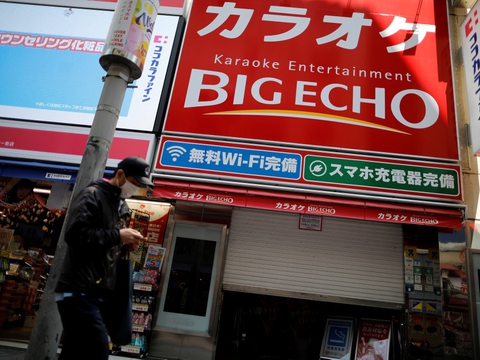 Mand med beskyttelsesmaske foran midlertidigt lukkede karakokeklubber i Tokyo. Men karaokeentusiaster i Japan kan nu igen komme til at synge, hvis de er forsigtige under deres optrædener.