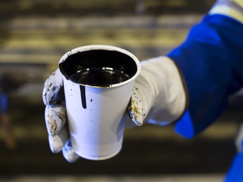 En arbejder holder en stor kop med olie. Ifølge en rapport bør Norge stoppe med at lede efter fossilt brændsel, lade være med at udvide infrastrukturen i industrien og forbyde de mest forurenende og miljøskadelige former for olie- og gasudvinding.