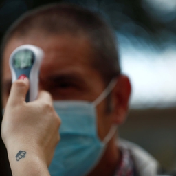 Socialarbejder Tamara Corona tager en besøgendes temperatur på et plejehjem ved Madrid.
