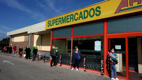 Kunder holder fysisk afstand, mens de venter på, at det bliver deres tur til at handle ind i et supermarked i Grinon i Spanien.