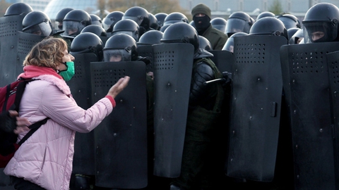 En kvinde diskuterer med betjente i kampudstyr, der søndag holder centrum af Minsk belejret under nye store protester mod regimet.