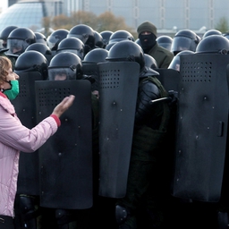 En kvinde diskuterer med betjente i kampudstyr, der søndag holder centrum af Minsk belejret under nye store protester mod regimet.