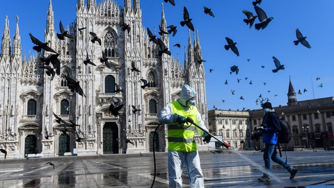 Iført beskyttelsesdragt sprøjter en medarbejder desinficerende væske på Piazza Duomo i storbyen Milano i det nordlige Italien tirsdag. Landet vil i endnu mindst to uger frem være lukket ned på grund af coronavirusset.