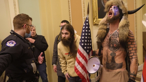 En ledende figur i den kontroversielle konspirationsbevægelse QAnon ved navn Jake Angeli også kendt som "Q Shaman" spillede en synlig rolle under onsdagens optøjer i Kongressen.