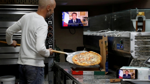 En ansat i et pizzeria i den sydfranske by Nice følger med i præsident Emmanuel Macrons tale til nationen mandag aften.