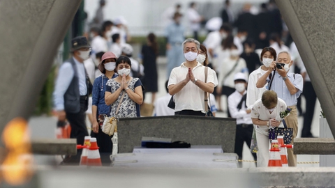 Folk beder for ofrene for atombomben i 1945 med masker på under en ceremoni i Fredsmindeparken i Hiroshima.