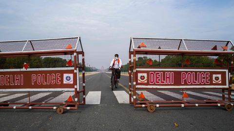 En cyklist i New Delhi kører gennem en afspærring på den mennesketomme boulevard Rajpath, der fører op til præsidentpaladset. Hele Indien lukker ned ved midnat på grund af coronavirus.