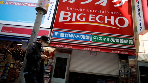 Mand med beskyttelsesmaske foran midlertidigt lukkede karakokeklubber i Tokyo. Men karaokeentusiaster i Japan kan nu igen komme til at synge, hvis de er forsigtige under deres optrædener.