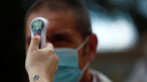 Socialarbejder Tamara Corona tager en besøgendes temperatur på et plejehjem ved Madrid.
