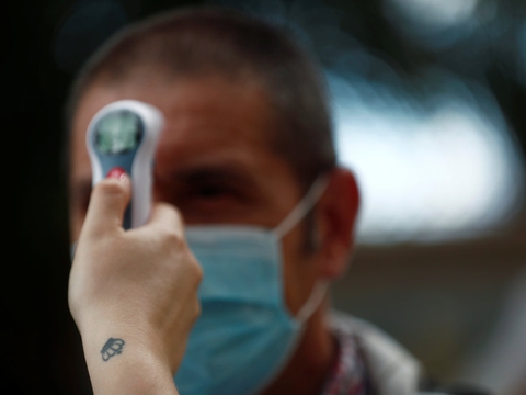 Socialarbejder Tamara Corona tager en besøgendes temperatur på et plejehjem ved Madrid.
