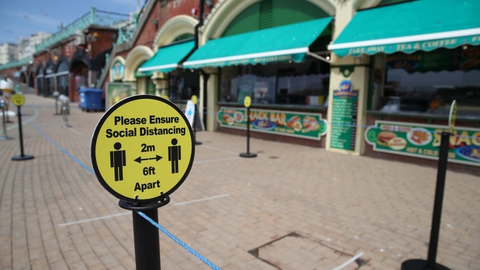 Store dele af Storbritannien er fortsat lukket ned, og overalt er der påmindelser om at holde afstand til hinanden - som her ved en strandpromenade i badebyen Brighton i det sydlige England.
