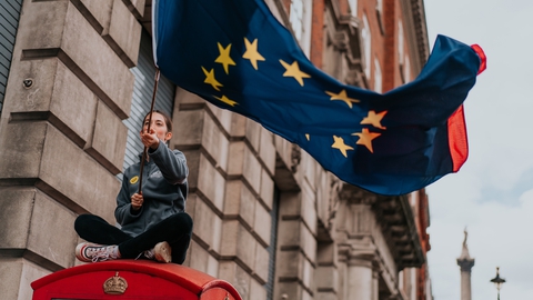 En EU-tilhænger vifter med unionens flag på toppen af en britisk telefonboks. (Foto: Brunel Johnson/Unsplash)